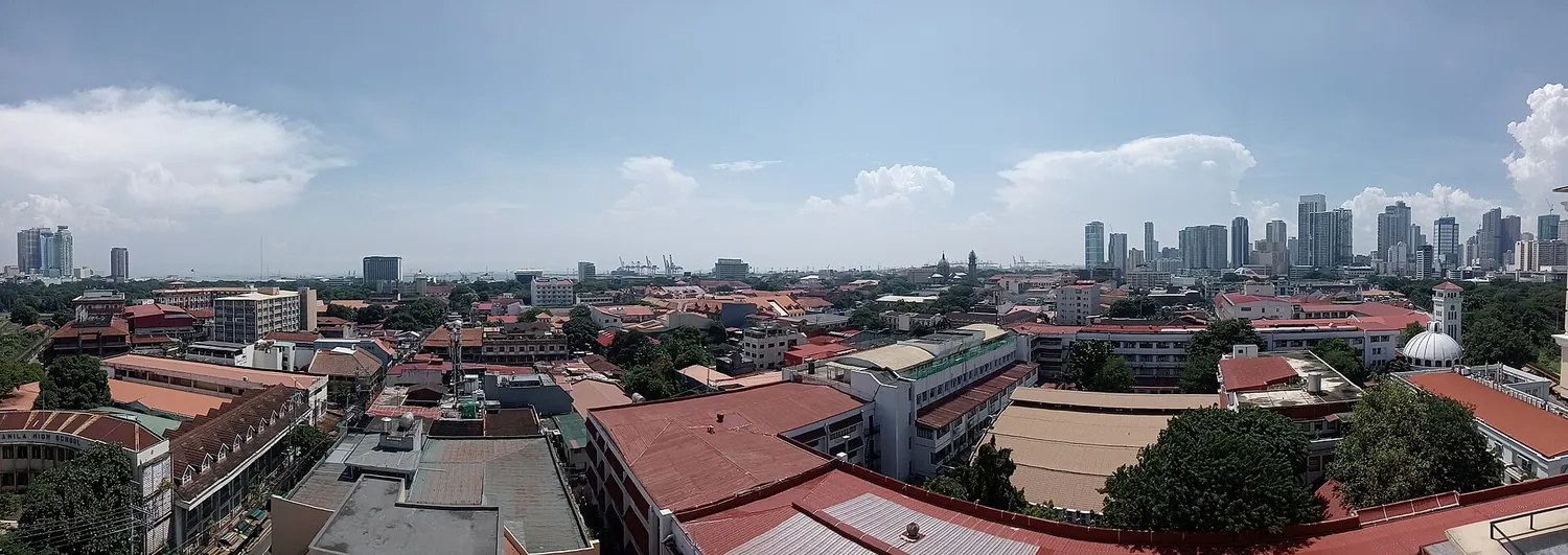 Utsikt over takene i Intramuros med høyhusene i Manila bak