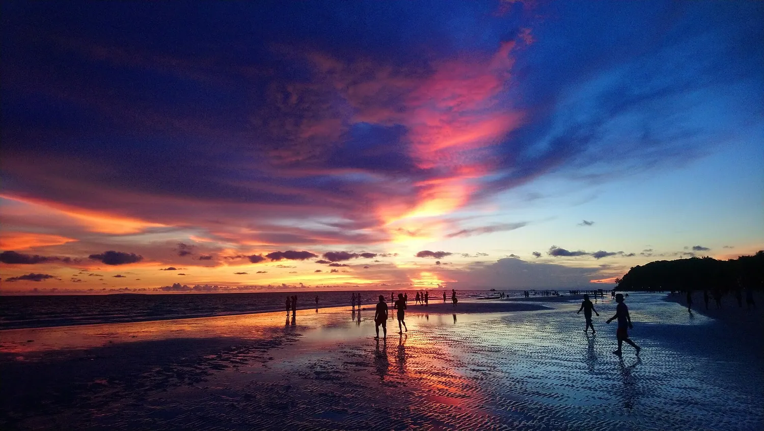 Solnedgang over White Beach på Boracay med badende i vannkanten
