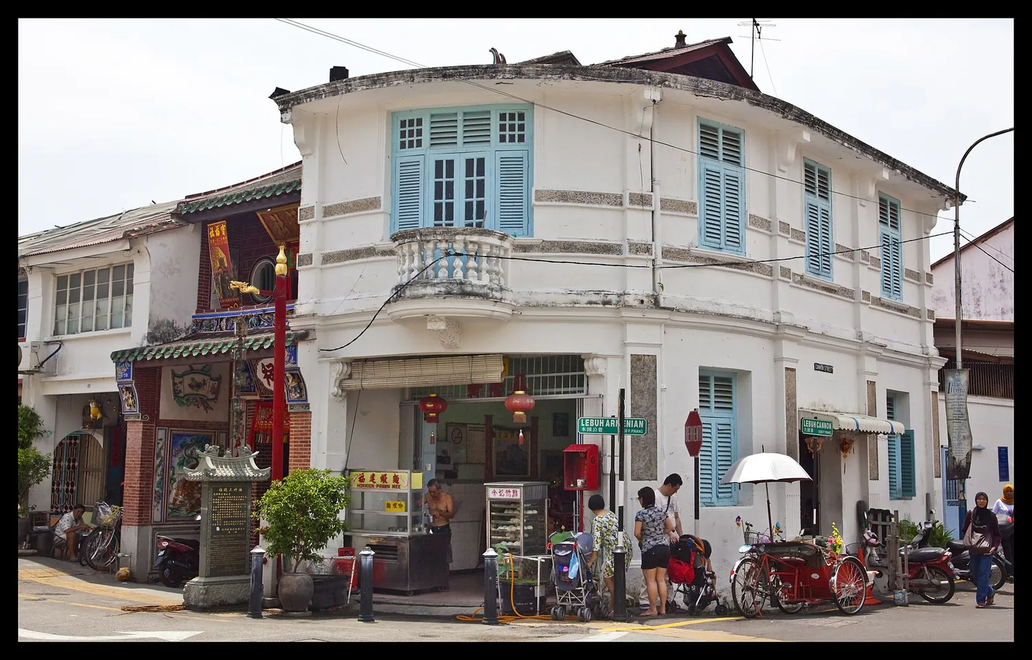 Gatehjørne i George Town på Penang med gammelt butikkhus og trishaws