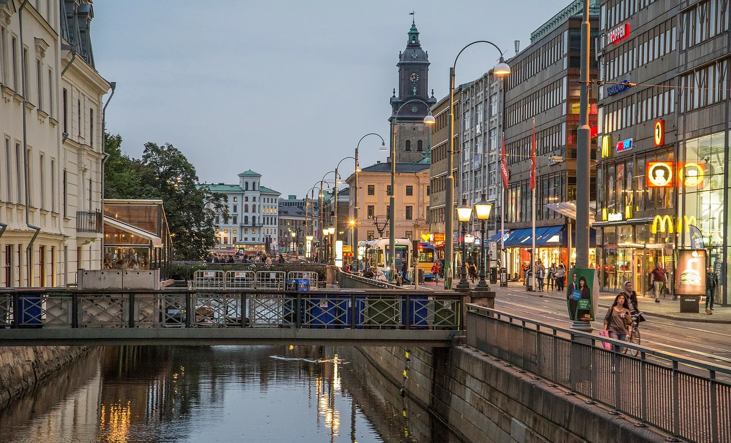 Kanal i Göteborg med bro, sporvogn og butikkgate speilet i vannet
