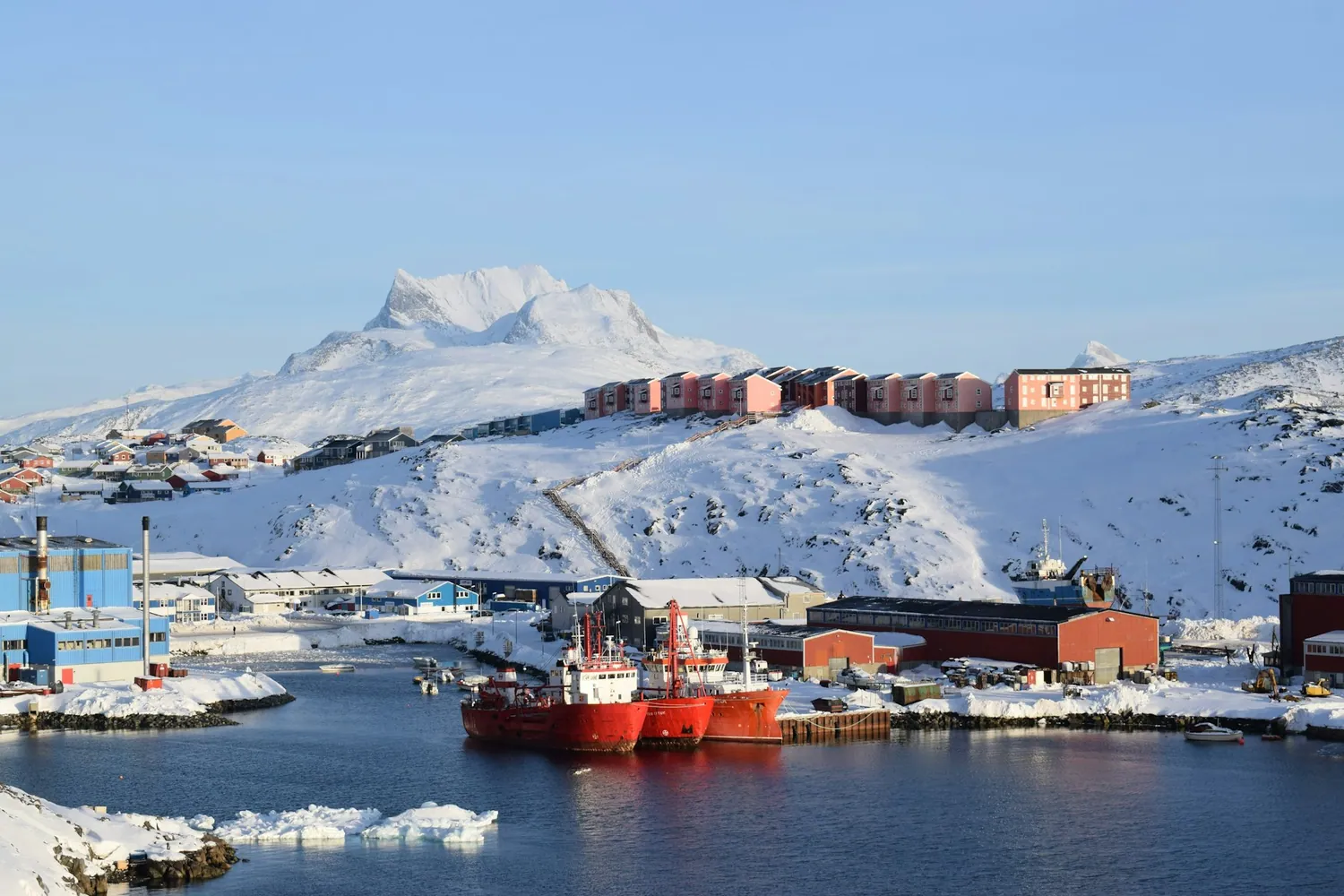 Fargerike hus og isfjell i havnen på Grønland